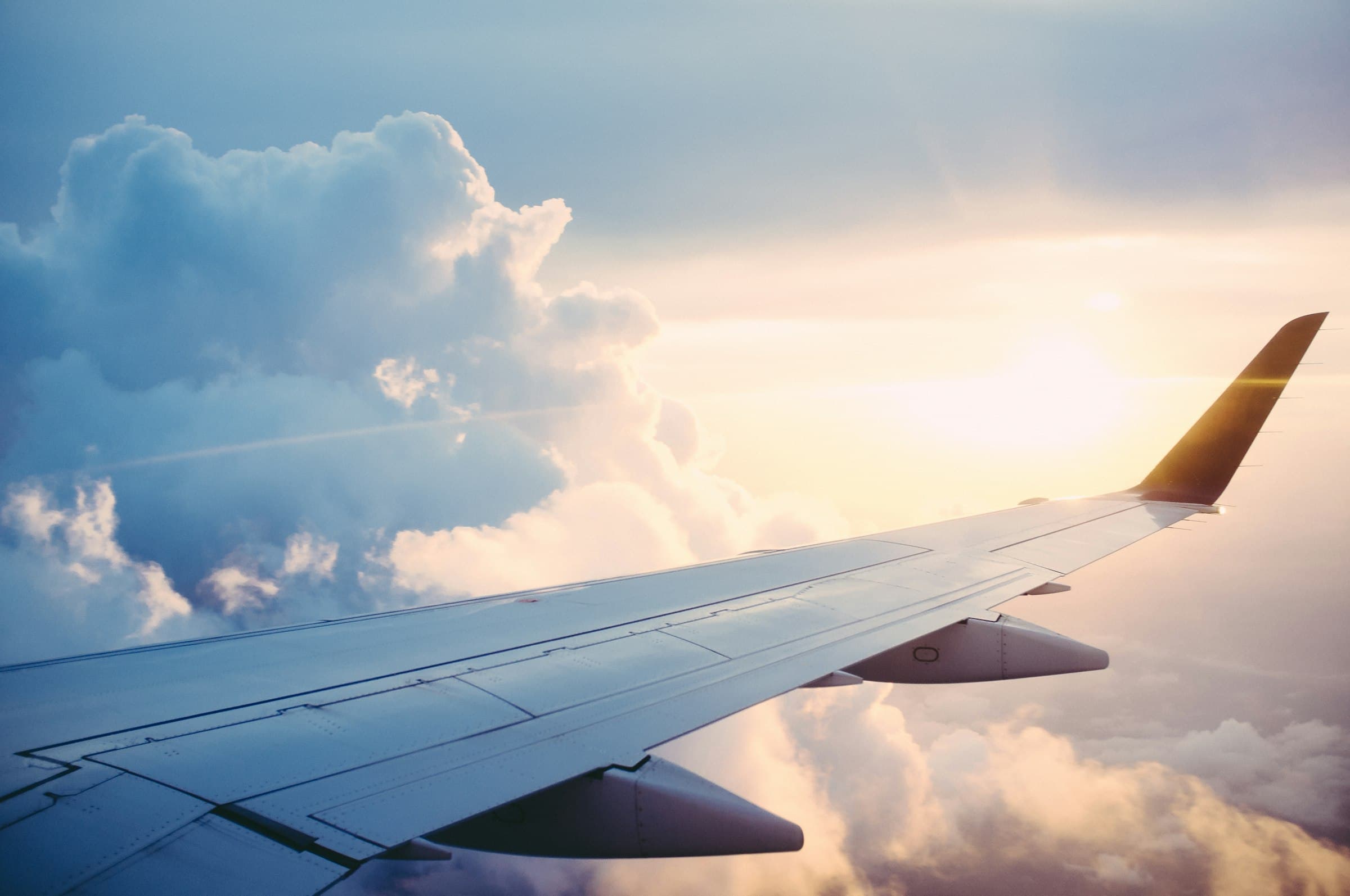 View of an airplane wing above the clouds at sunset